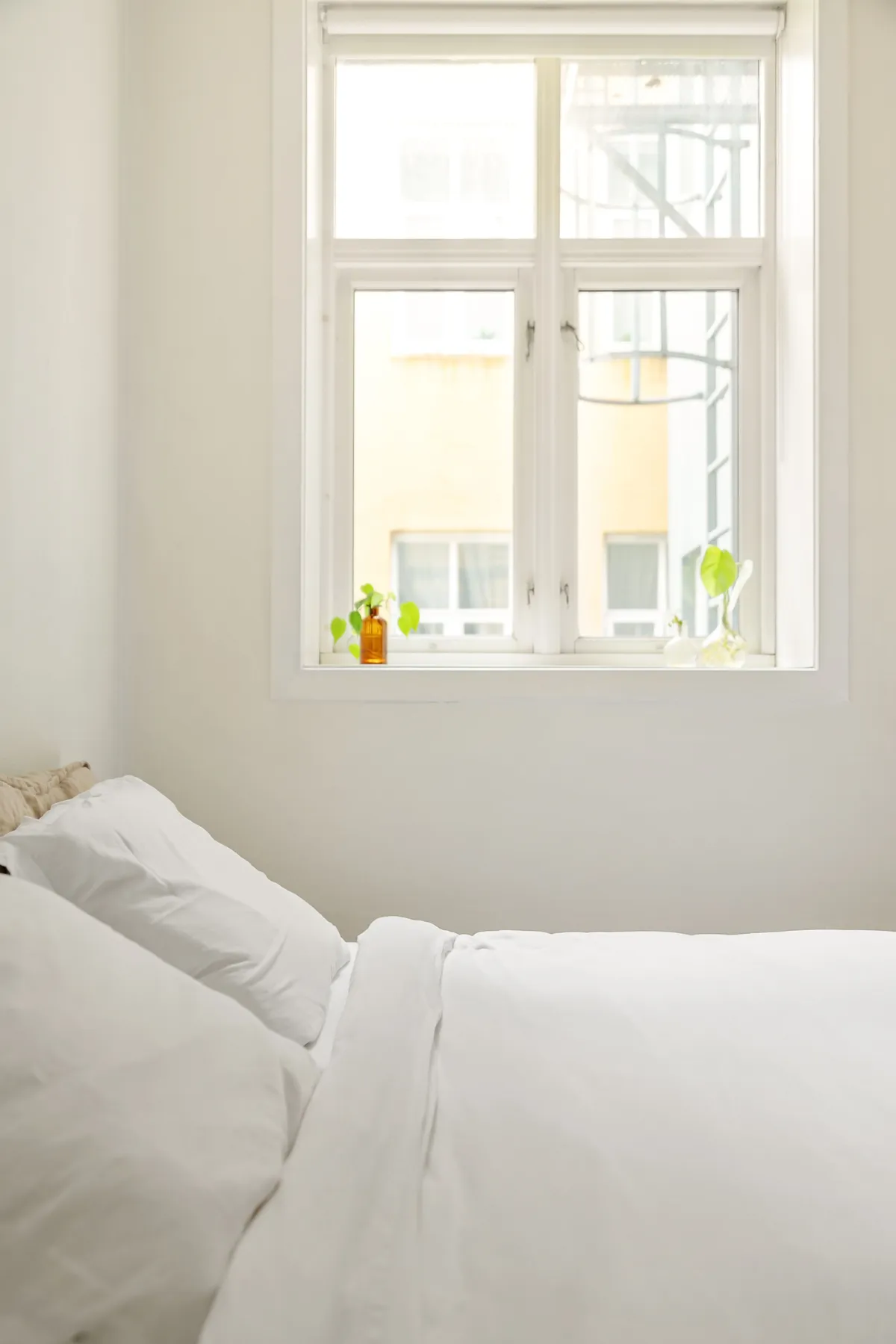 A bright, airy bedroom with crisp white bedding and an open window letting in fresh air.