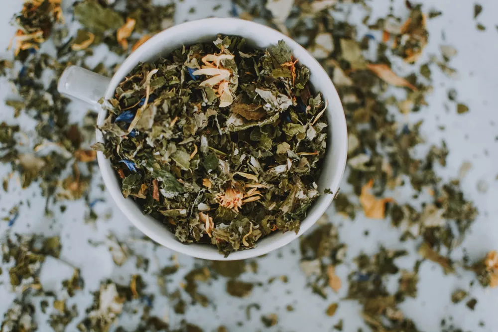 A cup of loose-leaf herbal tea seen from above, part of a calming evening wind-down routine.