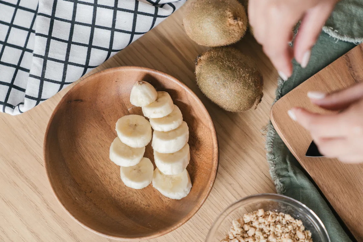 Kiwi, banana and oats on a wooden board — sleep-friendly evening foods.
