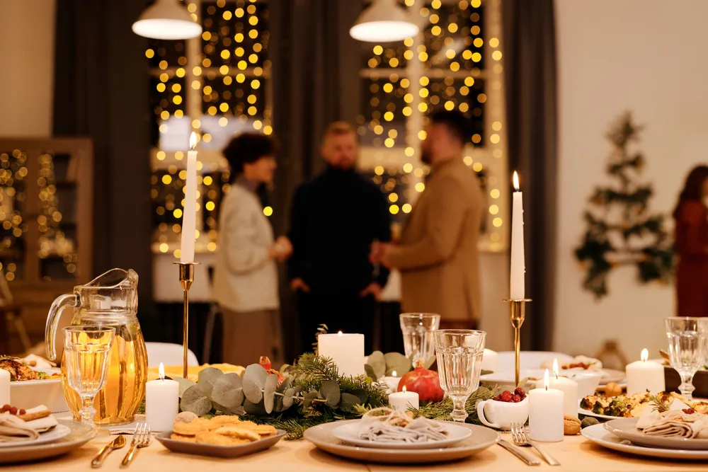 A table set with food and lit candles in the evening, with people talking in the background.