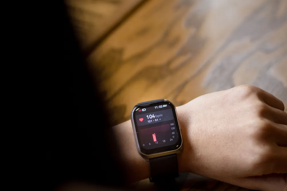 A smartwatch on a wrist showing a heart-rate reading of 104 beats per minute.