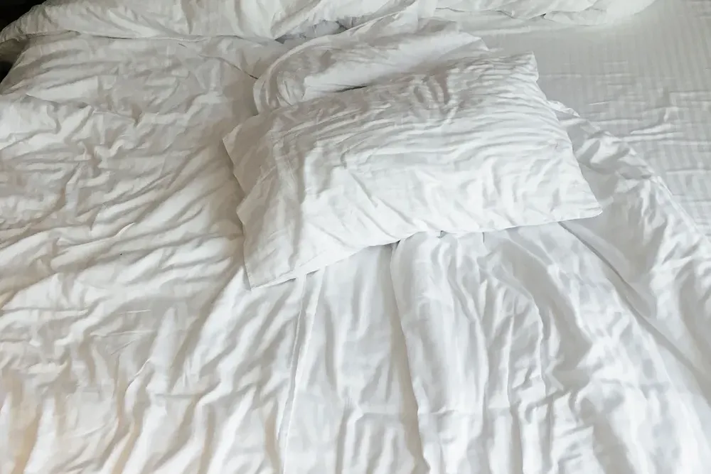 Crisp white pillows and bedding on a bed in soft daylight.