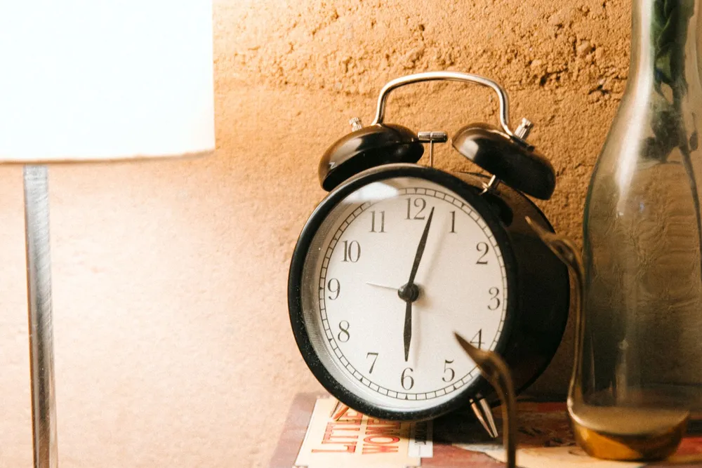 A vintage analogue alarm clock on a table in warm light.