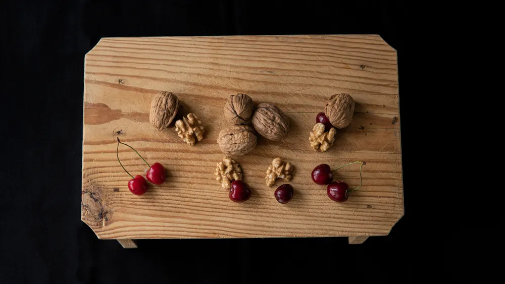 Walnuts and fresh cherries on a wooden board — two foods that naturally contain melatonin.