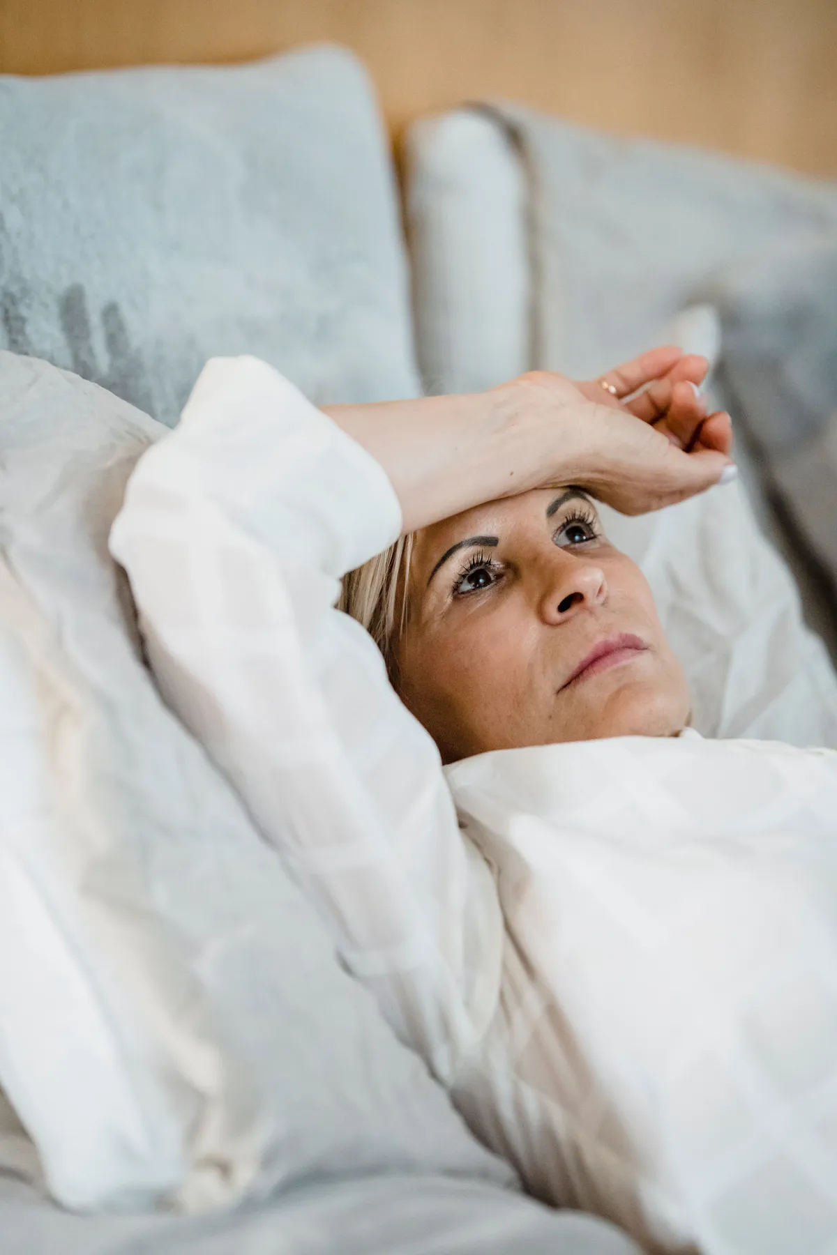 Woman in her mid-40s lying awake in bed at night, unable to sleep.
