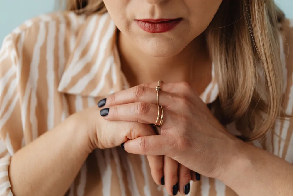 Close-up of a woman's hands clasped together in her lap.